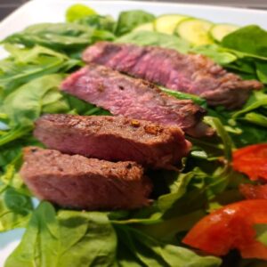 Medium-rare steak over a bed of greens