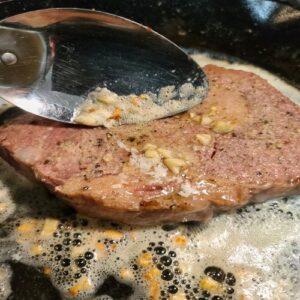 Spoon melted butter and garlic over steak