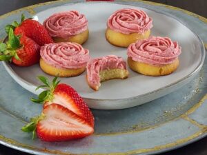 fresh strawberries accent this strawberry frosting atop a lemonade flavored sugar cookie.